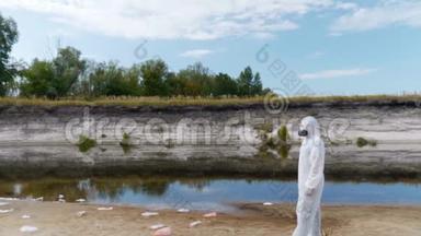 穿着防护服和呼吸器的人站在塑料垃圾桶中，靠近一条干涸的河流，打开摄像机